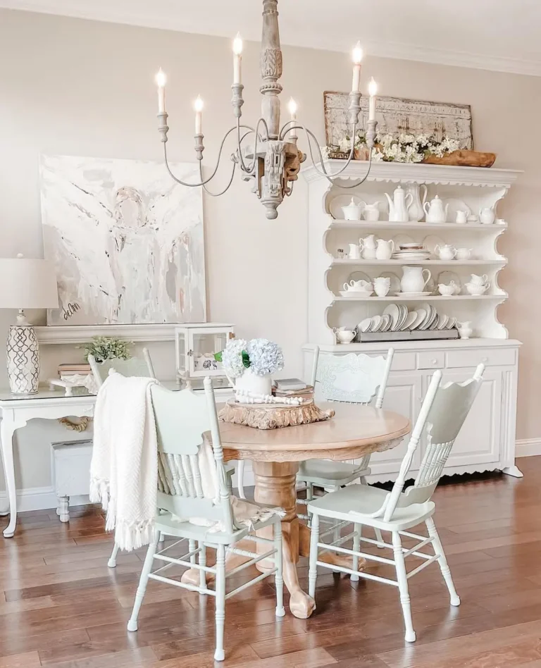 a french country-inspired dining room with a round wooden table and chairs complete with a candle-chandelier that add visual interest and warm glow to the room