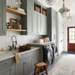 a modern farmhouse laundry room with generous light green wall cabinets, shiplap walls, and some open shelving to complete the design