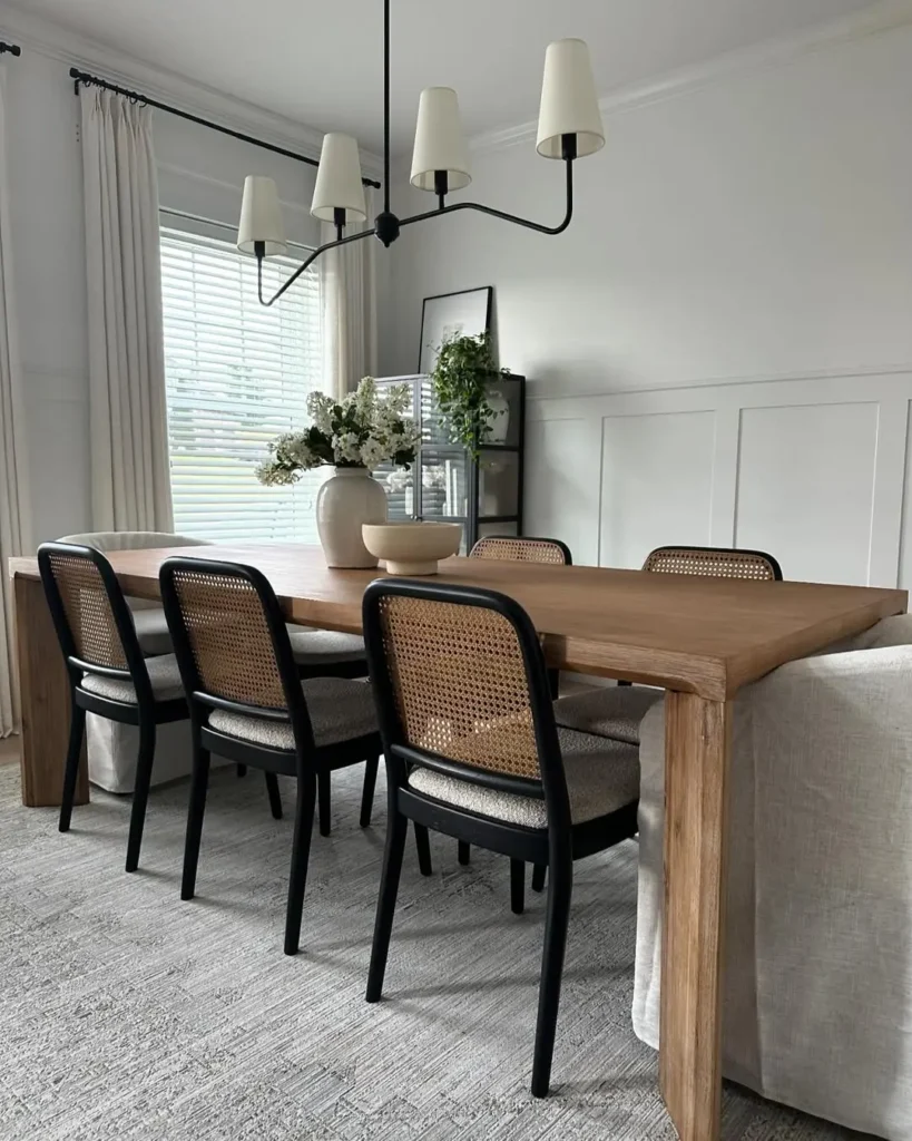 the wooden dining table, modern chairs, lighting fixture, and plant and less clutter all add to the organic modern feel in this dining room