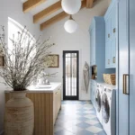 spacious with clean lines and simple design, this sleek and stylish modern laundry room showcases light blue cabinets with gold hardware