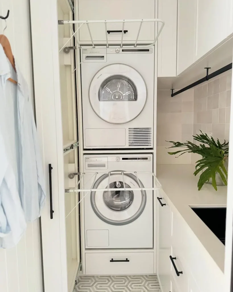 a small laundry in monochromatic tone and with stackable washer and dryer and clever pull out drying rack make this laundry room both efficient and modern