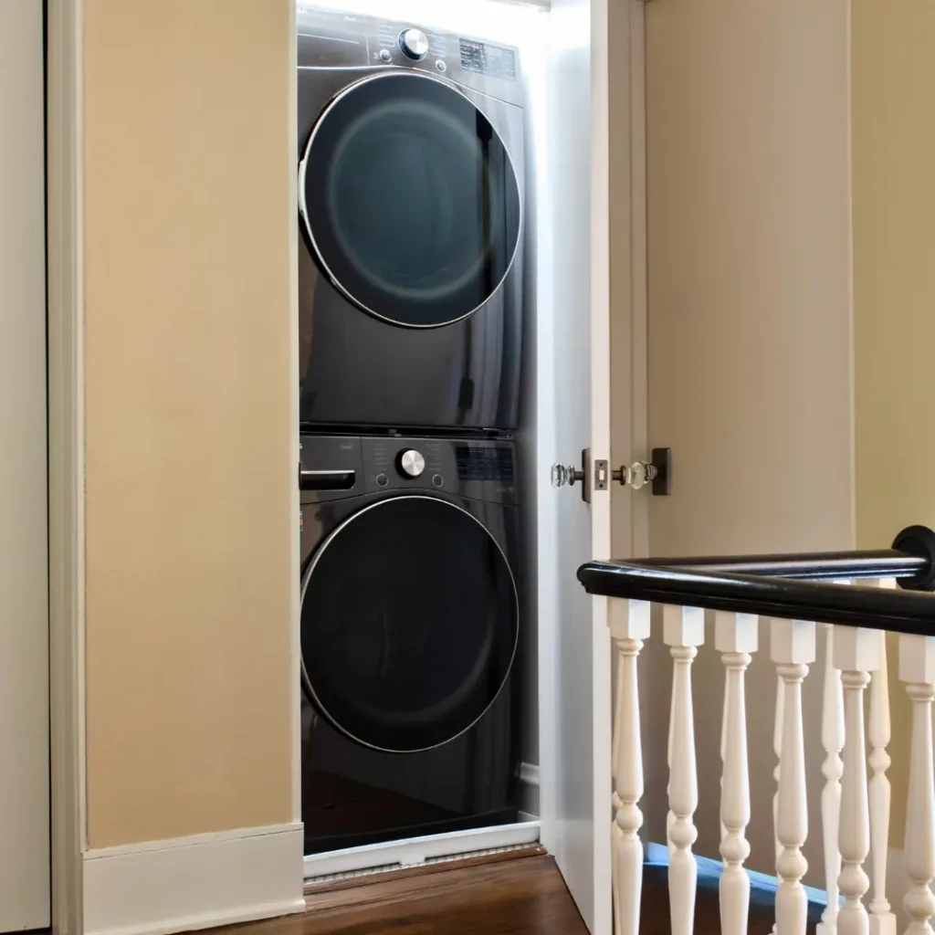a stackable washer and dryer installed on the upper floor of a house next to the stair balustrade provides convenience and space-saving benefits