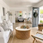 a light, bright, and airy living room interior with the perfect summer coastal decor vibe with a slipcover sofa, jute rug, and rattan coffee table