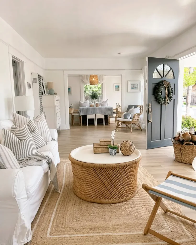 a light, bright, and airy living room interior with the perfect summer coastal decor vibe with a slipcover sofa, jute rug, and rattan coffee table
