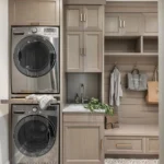a stackable washer and dryer integrated into beautifully made cabinets in a mudroom with a small sink and alcove bench