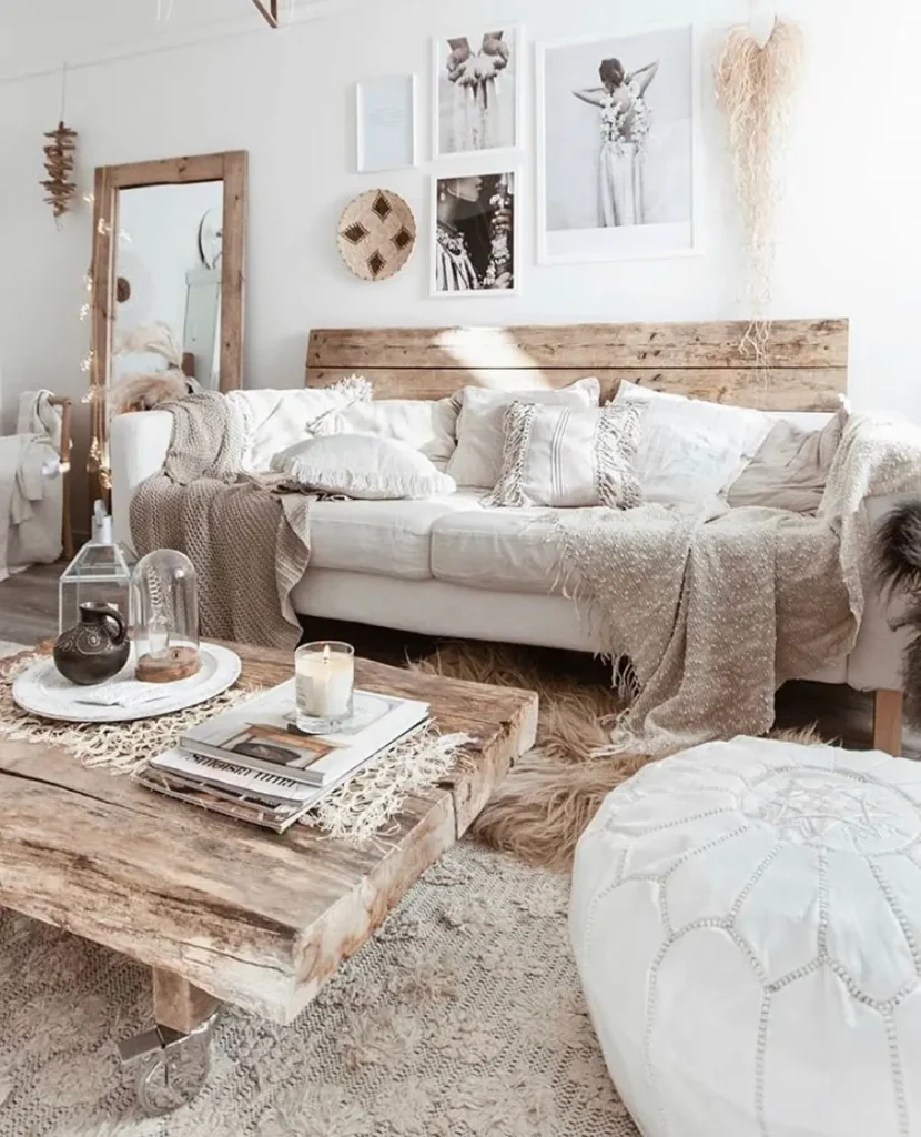 Bohemian-rustic style living room with a wooden coffee table, white sofa with neutral pillows and throws, wall art, a large mirror, and textured decor elements in natural tones.