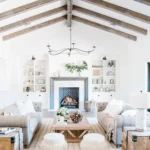 Rustic living room with exposed wood ceiling beams, neutral furniture, cozy textures, and a central wood coffee table styled with natural decor.