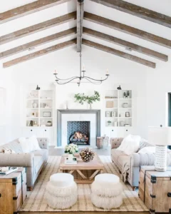Rustic living room with exposed wood ceiling beams, neutral furniture, cozy textures, and a central wood coffee table styled with natural decor.