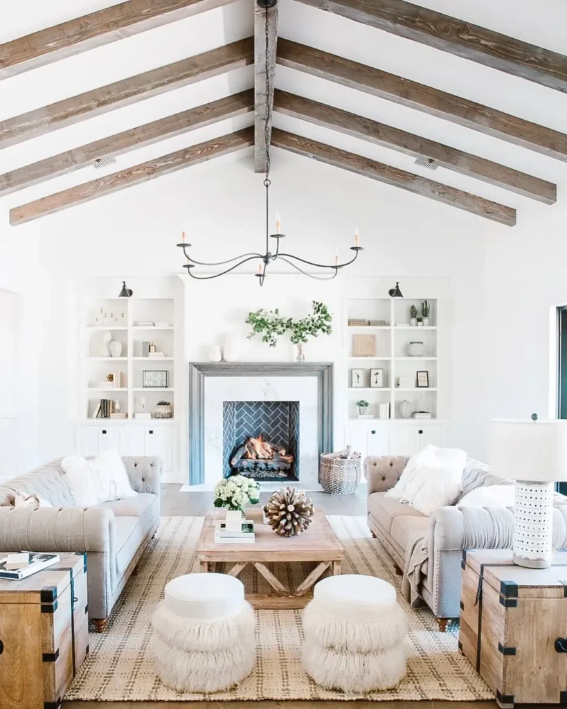 Rustic living room with exposed wood ceiling beams, neutral furniture, cozy textures, and a central wood coffee table styled with natural decor.