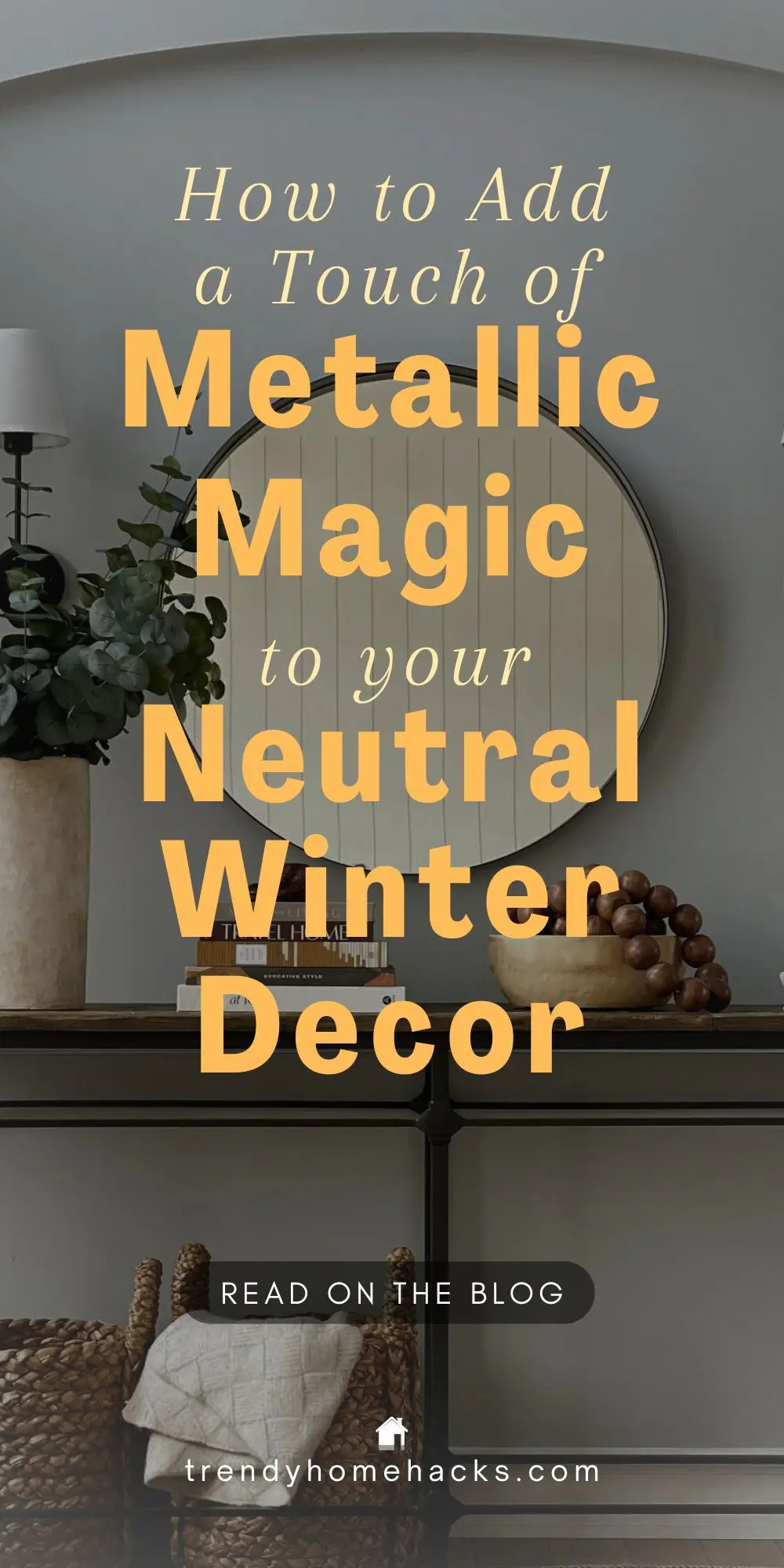 A modern console table with decorative items sits in front of a round mirror; overlaid text reads, "How to Add a Touch of Metallic Magic to your Neutral Winter Decor.