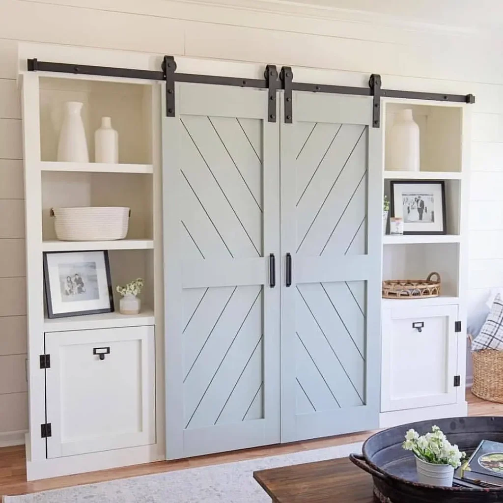 Built-in shelving unit with light blue sliding barn doors and white shelves, styled with decor items, baskets, and framed photos—perfect for complementing modern rustic bedroom furniture in your living space.