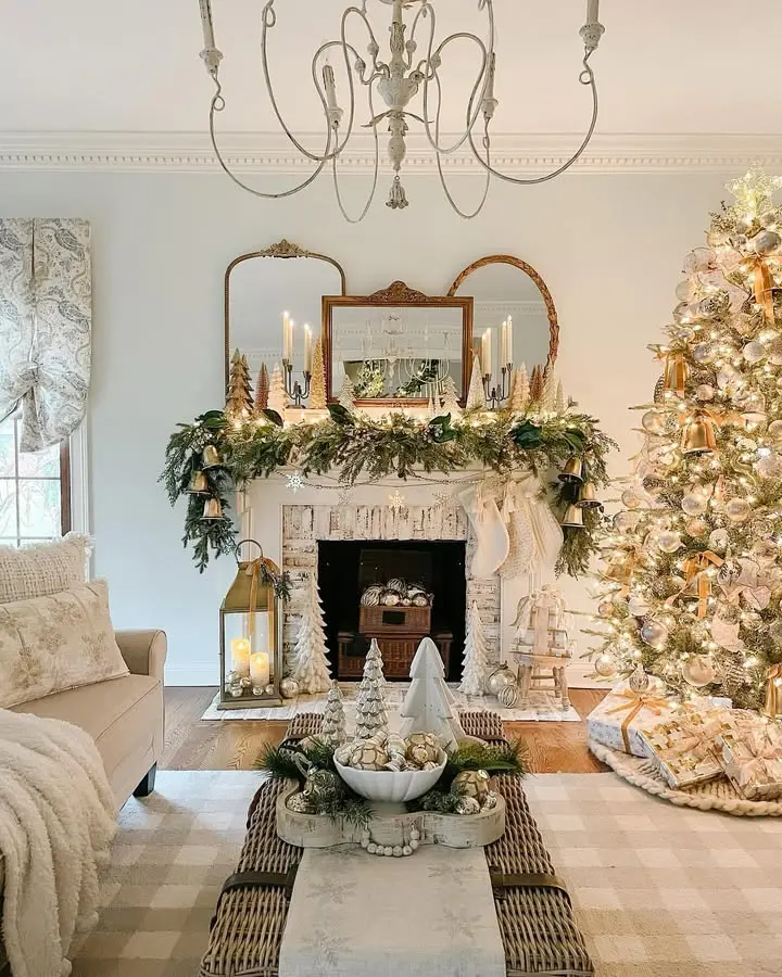 A living room decorated for Christmas with a lit tree, garland and candles on the mantel, stockings, festive ornaments on the coffee table, and touches of rustic and farmhouse Christmas decor throughout.