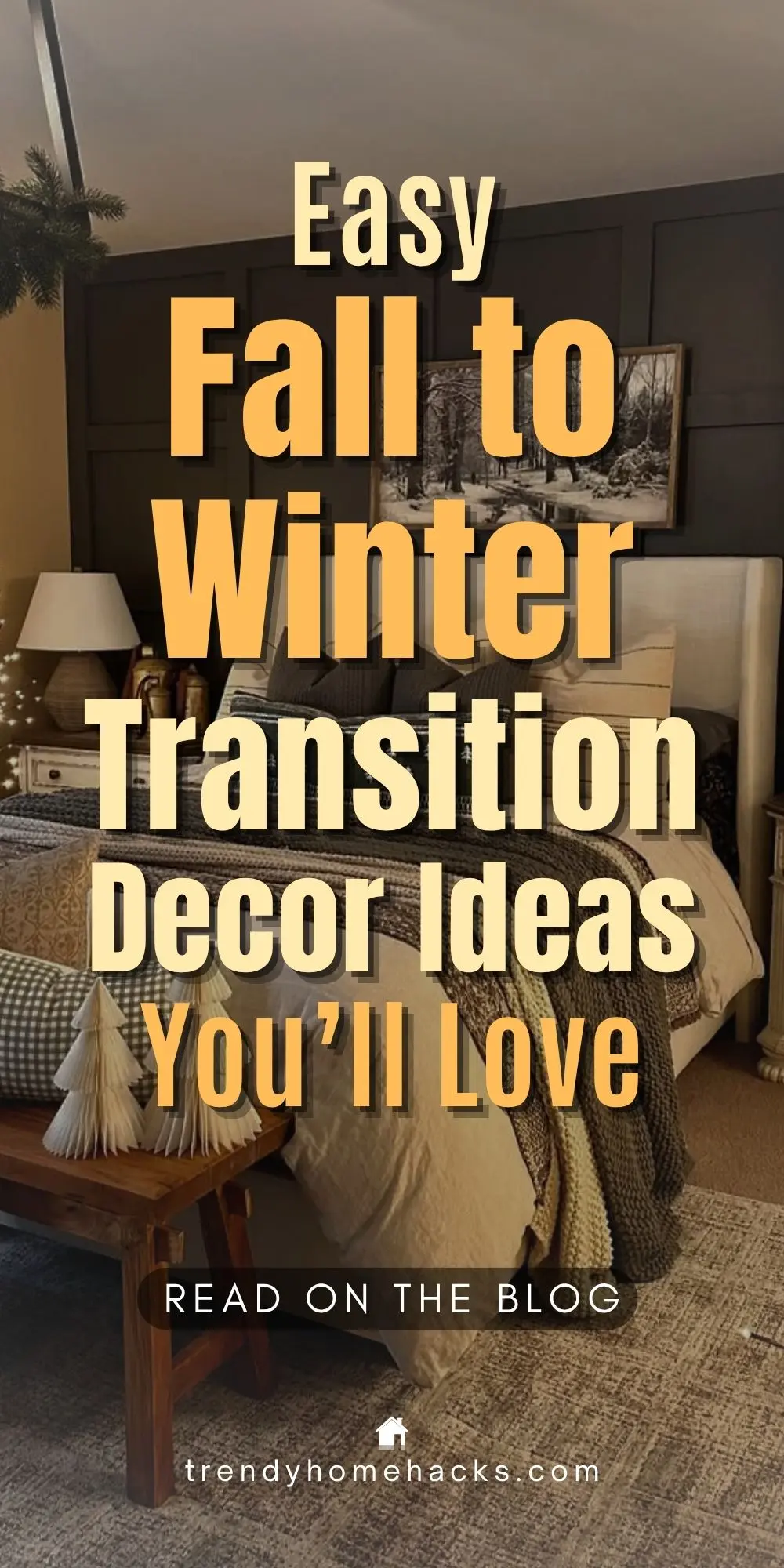 A cozy bedroom decorated for the fall-to-winter season transition featuring warm earth-tone bedding, a neutral area rug, white mini Christmas trees on a wooden bench, and a black accent wall with snowy landscape art. Overlay text reads: "Easy Fall to Winter Transition Decor Ideas You’ll Love."