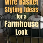 Rustic farmhouse vignette featuring a wire basket filled with greenery and white pumpkins, styled on vintage books and wooden tabletop, showcasing simple farmhouse wire basket decor ideas.