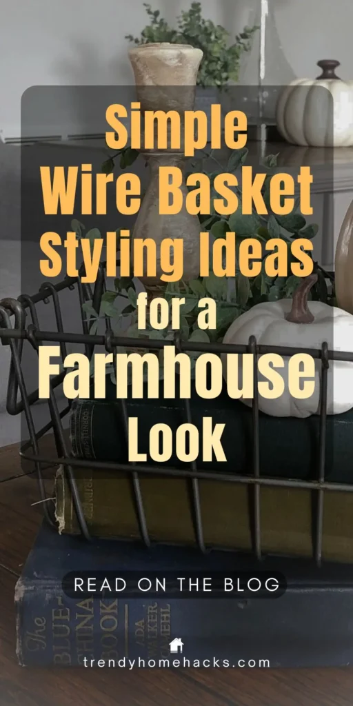 Rustic farmhouse vignette featuring a wire basket filled with greenery and white pumpkins, styled on vintage books and wooden tabletop, showcasing simple farmhouse wire basket decor ideas.