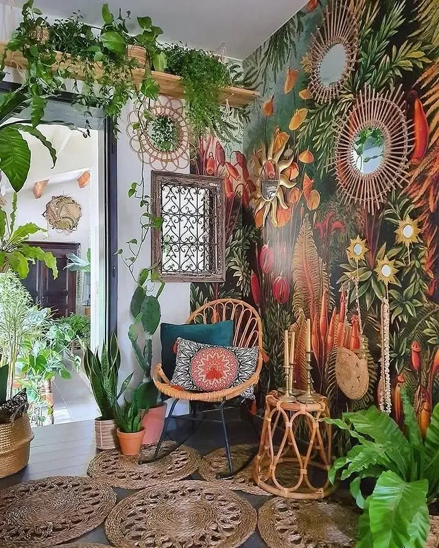 A cozy corner with a rattan chair, woven rugs, potted plants, and a vibrant tropical mural on the wall showcases Bohemian living room decor with eclectic finds, accented by decorative mirrors and natural light.
