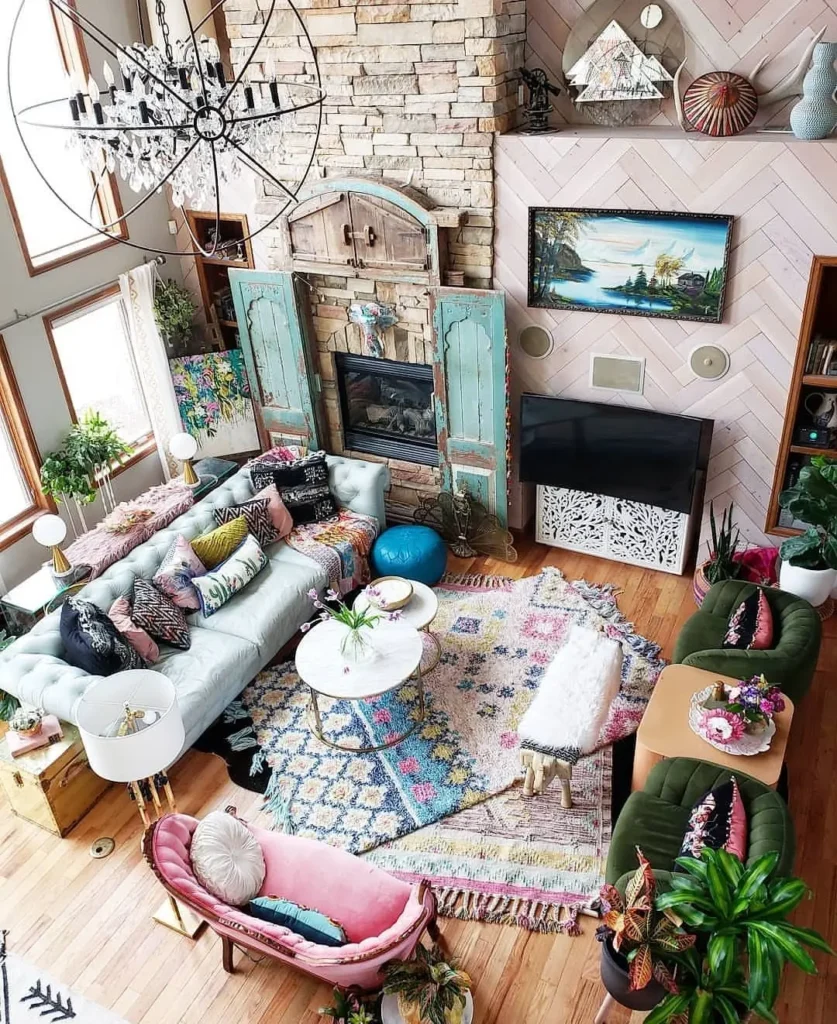 A colorful, eclectic living room features layered rugs, assorted sofas, a stone fireplace, indoor plants, and unique decorative items all thoughtfully arranged on wooden floors.