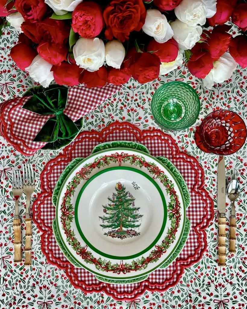 An easy Christmas table setting using the right table linen features Christmas-themed plates, red and green glassware, a floral centerpiece, and patterned linens in festive red, green, and white.