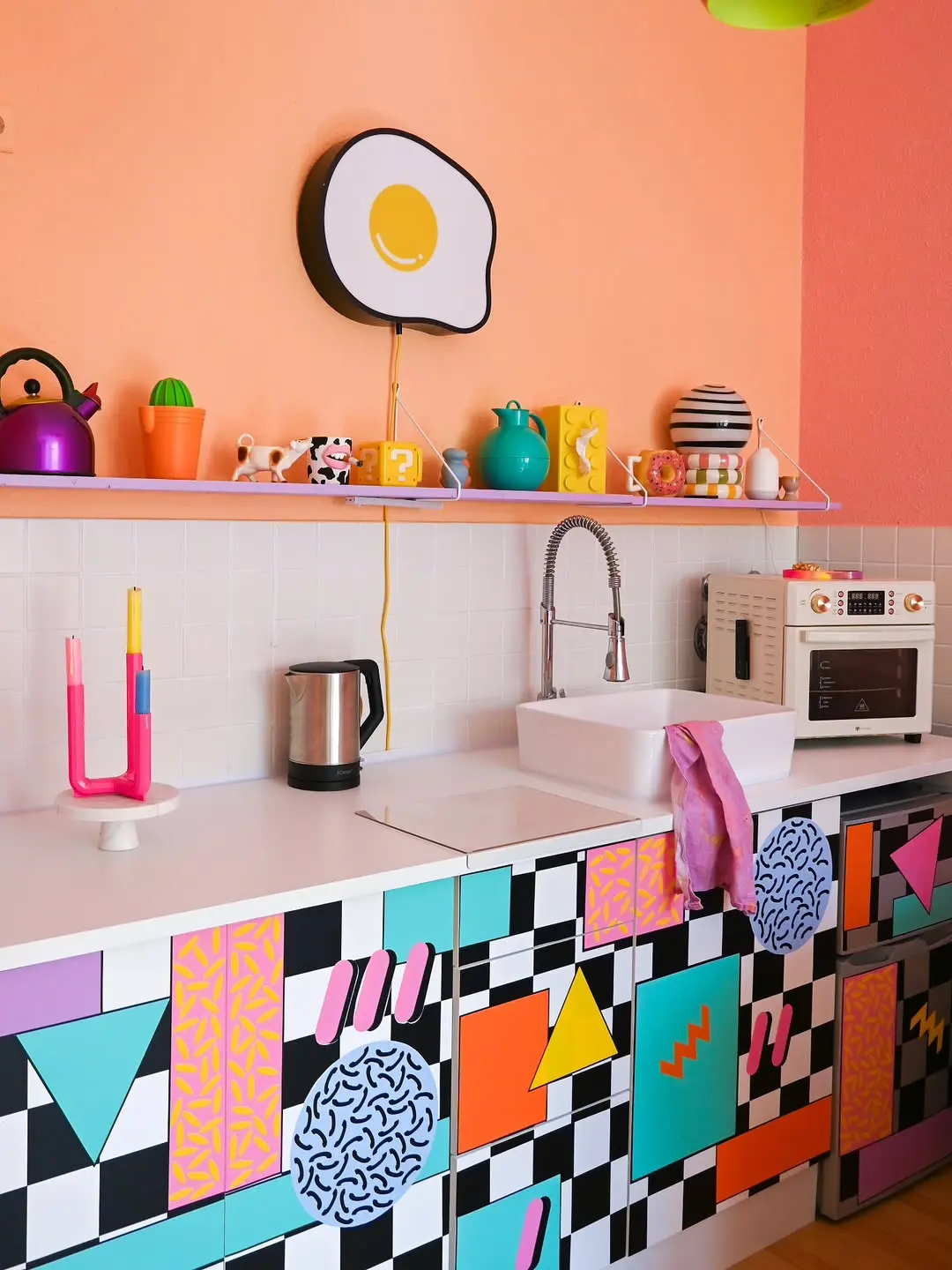 Colorful funky kitchen with geometric cabinet patterns, playful wall art, and bold pink and orange accents, a creative, personality-filled space that inspires bold design ideas.