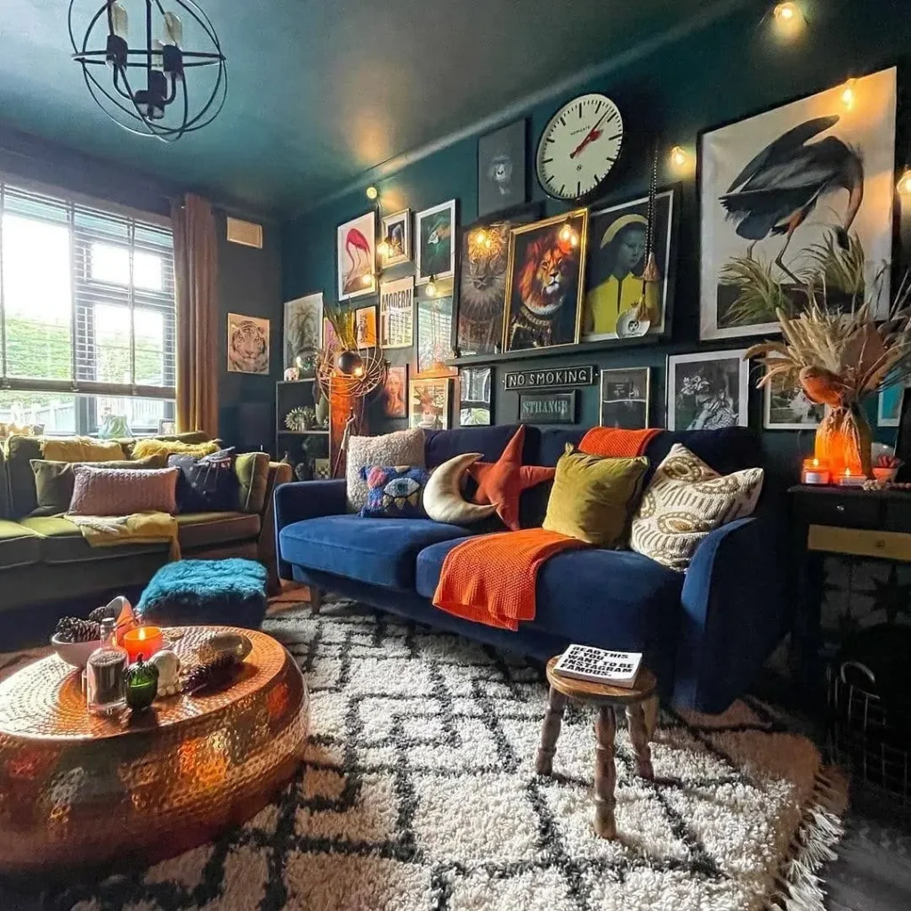A cozy maximalist living room with eclectic decor, featuring a blue sofa, patterned rug, copper coffee table, various pillows, and a gallery wall covered with framed art and a large clock.