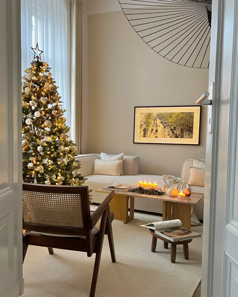 A cozy living room with a decorated Christmas tree, lit candles on a coffee table, modern furniture, and framed art on a beige wall—perfect for inspiring Christmas living room decor ideas for small spaces.