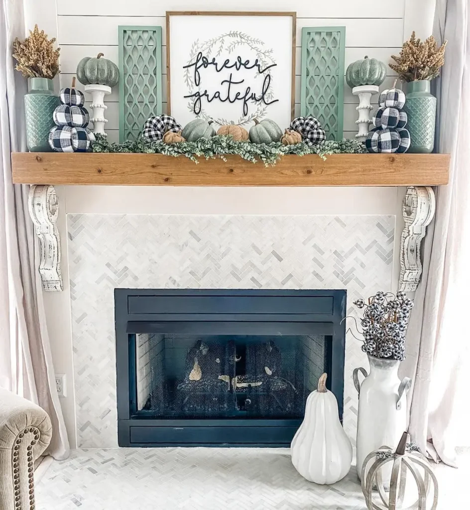 A decorated fireplace mantel with pumpkins, greenery, and vases sits below a sign reading "forever grateful." Modern farmhouse touches and handmade fall decor in neutral and blue tones create a cozy, autumn-themed display.