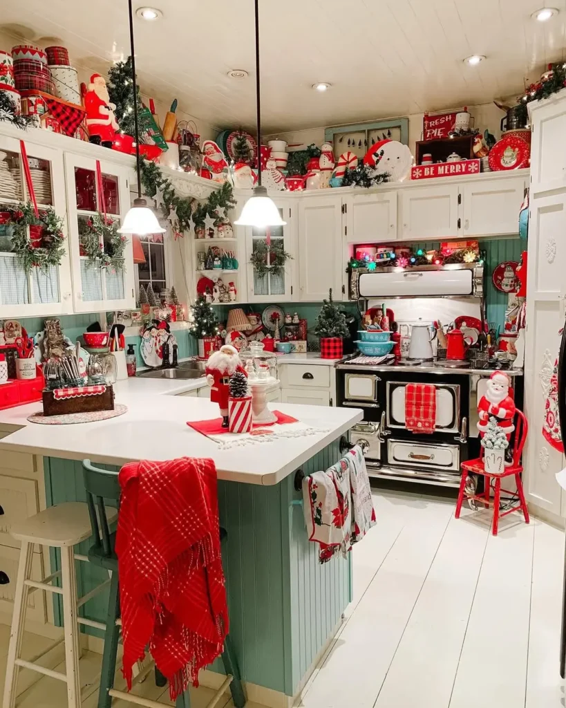Festive kitchen decorated for Christmas with funky red and white accents, dishware, holiday towels, and various seasonal ornaments on counters and shelves.