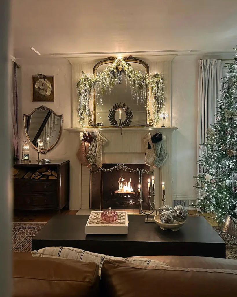 A living room with a lit fireplace, Christmas stockings, elegant christmas mantel decor ideas for small spaces, a mirror, Christmas tree, candles, and a chessboard on a coffee table.