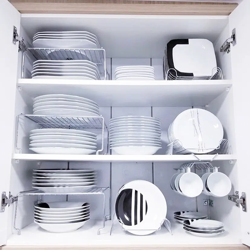 Open kitchen cabinet with neatly organized white plates, bowls, and cups arranged on shelves and vertical organizers for a tidy look.