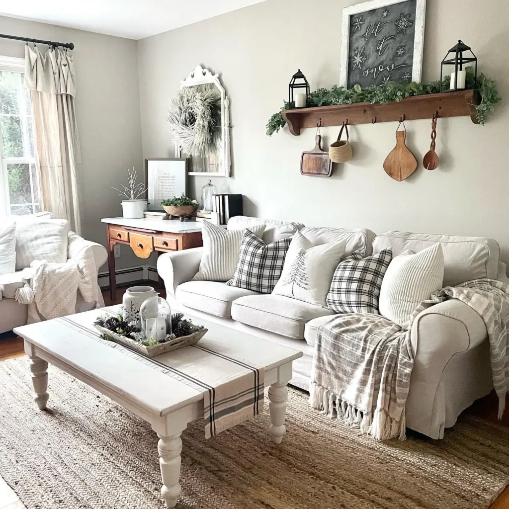 A cozy farmhouse rustic living room with a white sofa, plaid pillows, a striped coffee table, wall shelf with decor items, and natural light from a window.