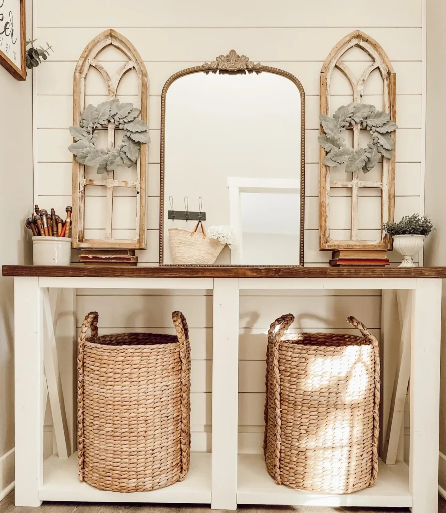 Rustic farmhouse entryway featuring a console table, arched mirror, vintage window decor, and woven baskets.