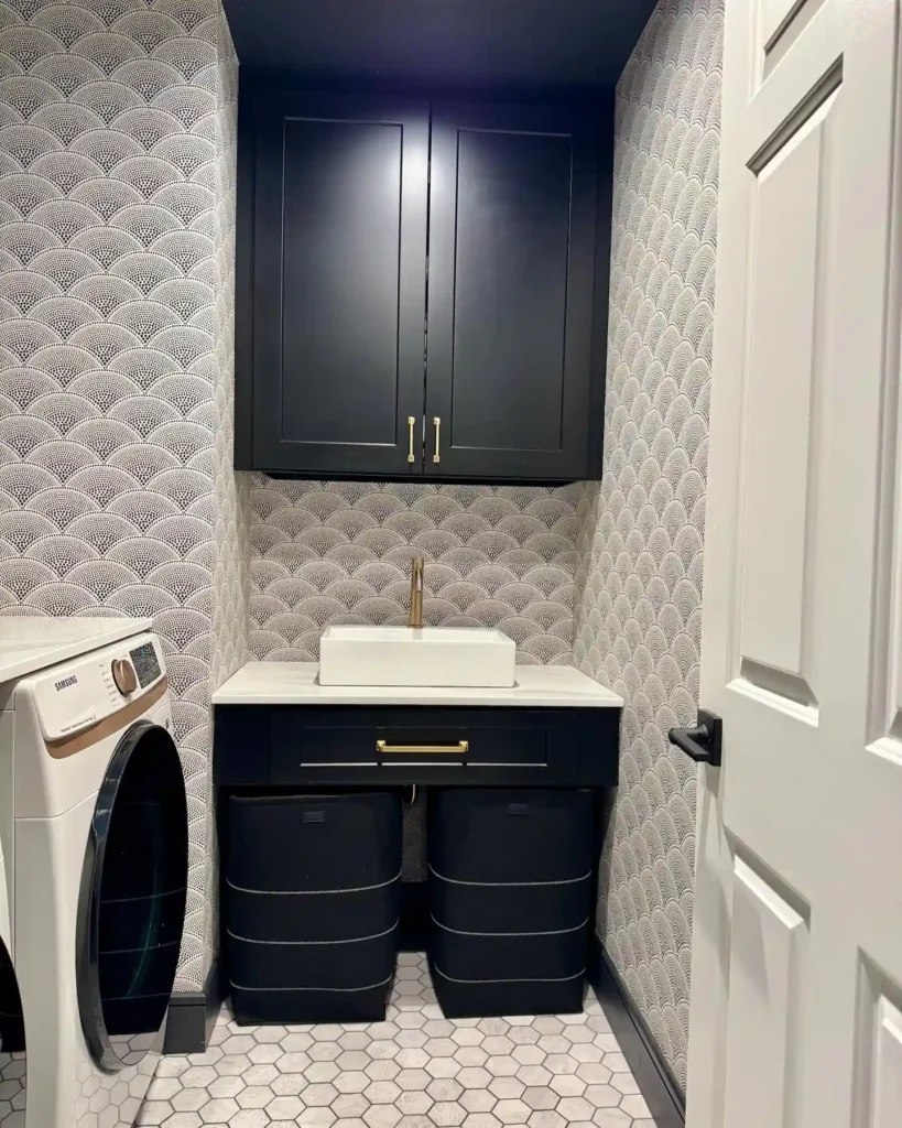 Small laundry room with glam scalloped wallpaper, black cabinetry, brass hardware, white sink, and hex tile flooring.