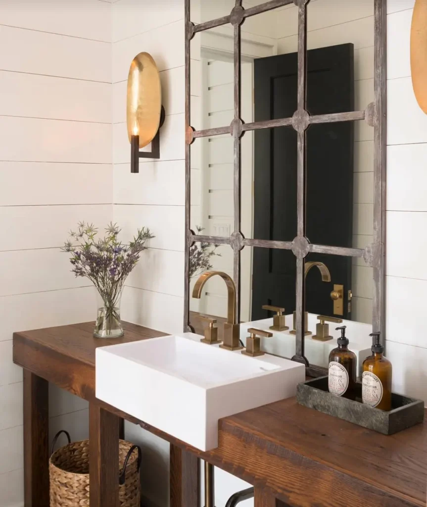 Industrial farmhouse bathroom vanity with vintage-inspired brass faucet, white vessel sink, reclaimed wood counter, grid-style mirror, and shiplap walls.
