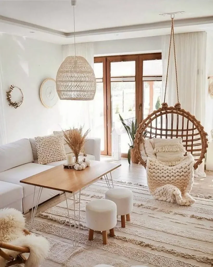 Boho living room with textured neutral area rug, hanging rattan chair, woven pendant light, and light wood coffee table.