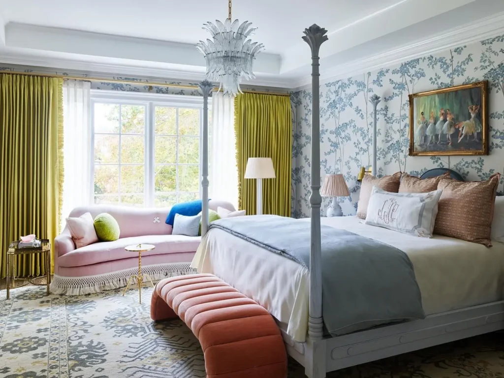 Colorful funky master bedroom with floral wallpaper, pink velvet sofa, four-poster bed, and bold green curtains.