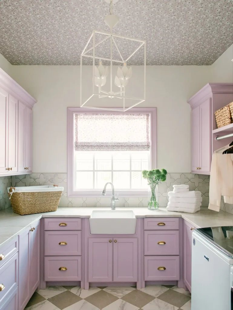 Lavender laundry room with farmhouse sink, patterned ceiling wallpaper, brass hardware, and decorative ceiling light fixture.