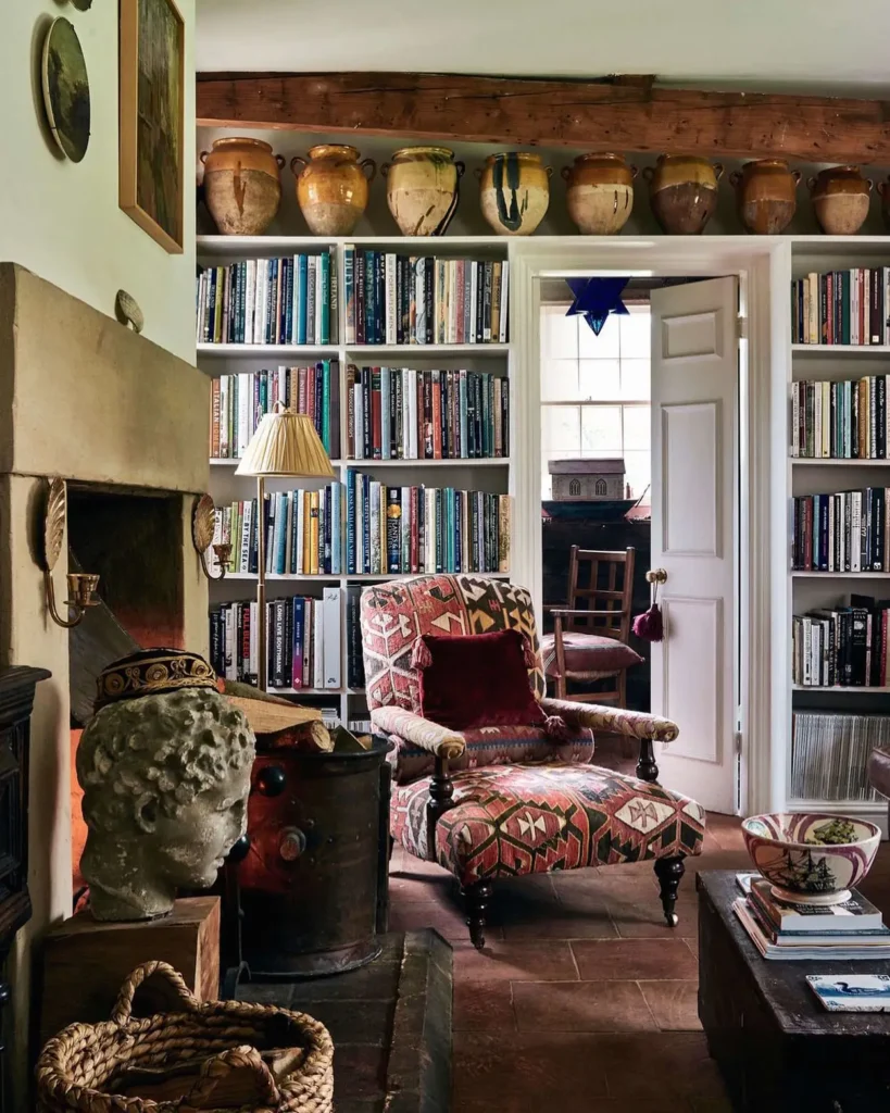 Vintage eclectic living room with built-in bookshelves, patterned armchair, and cozy fireplace.