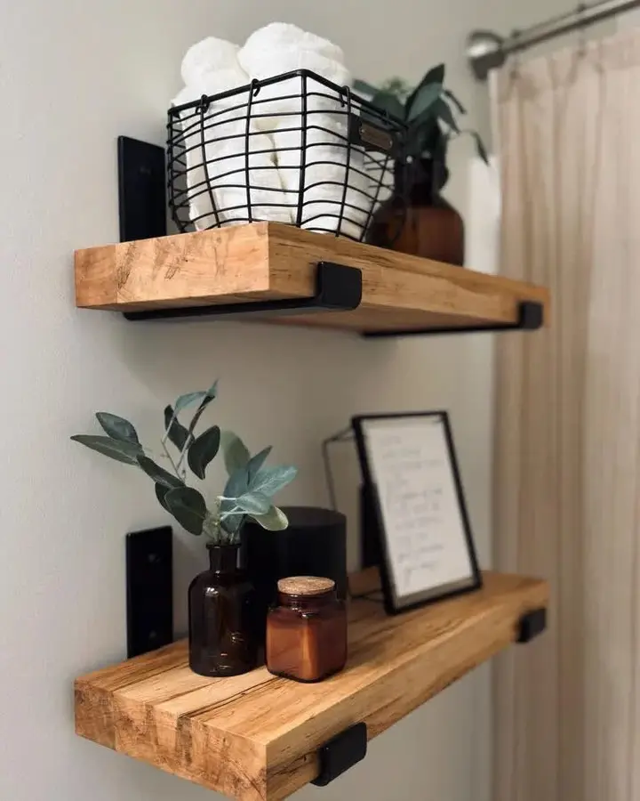 Farmhouse bathroom floating shelves with rustic wood planks, black metal brackets, wire basket towel storage, and modern decor accents.