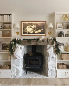 Farmhouse winter living room with a whitewashed stone fireplace, wood stove, evergreen garland, woven baskets, and neutral holiday accents